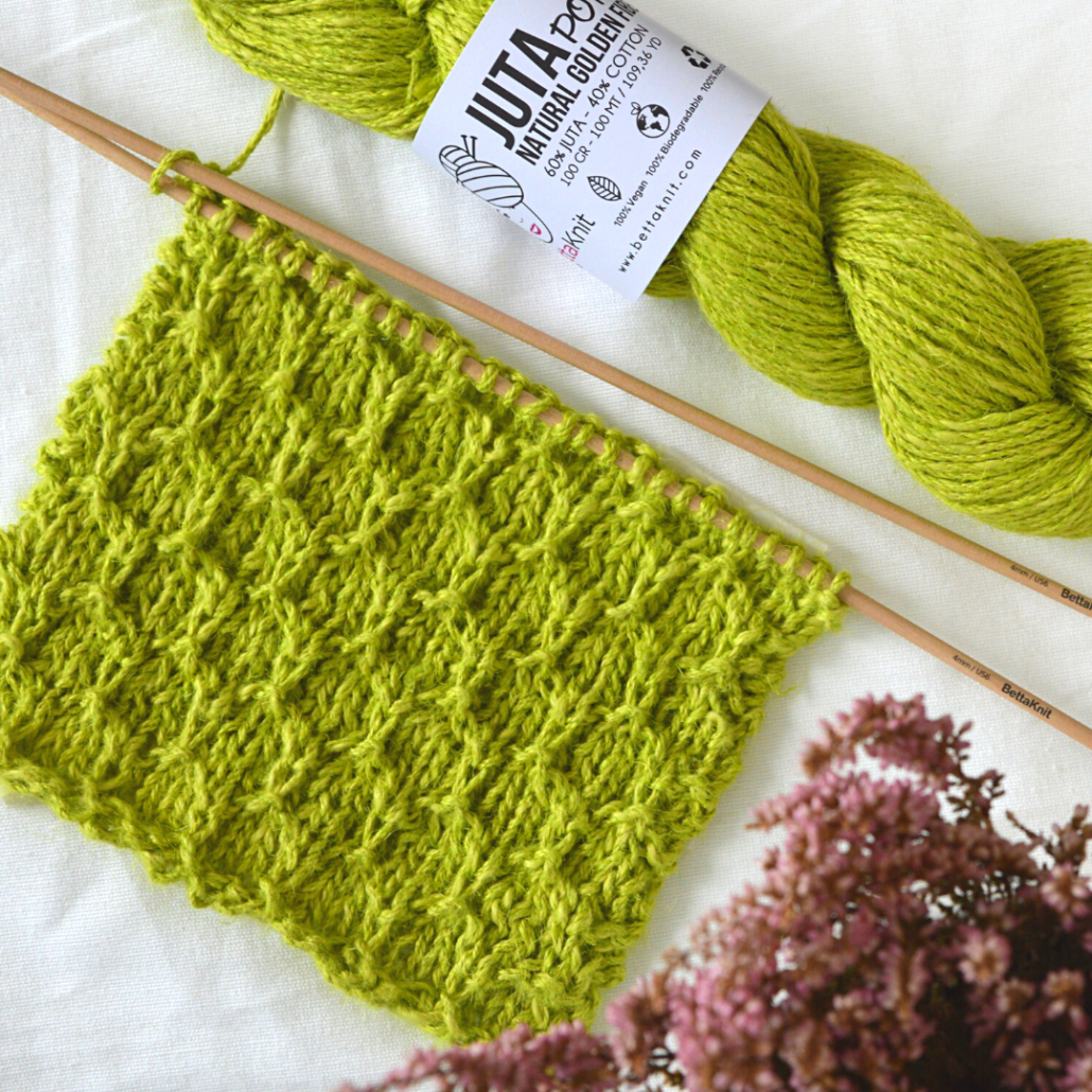 Il Punto Esagoni è un punto maglia che crea un motivo geometrico ad esagoni in rilievo su una base a maglia rasata. Per delineare gli esagoni si lavorano maglie passate a rovescio, sul lato rovescio del lavoro. Questo punto è perfetto per dare struttura ad accessori in juta, ma anche per coperte ed accessori per la casa.