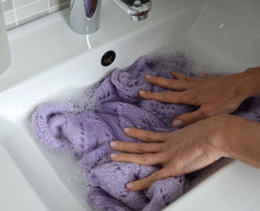 Maglione di lana fatto a mano pronto per essere lavato in una bacinella con acqua fredda